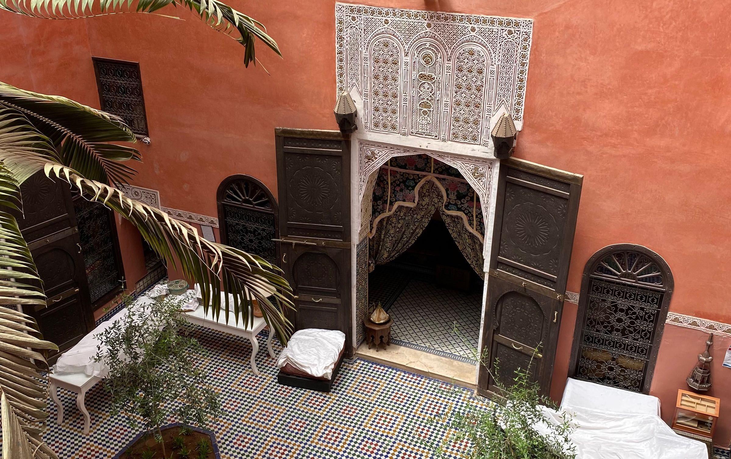 A traditional riad courtyard in Marrakesh with coral walls and mosaic tilework